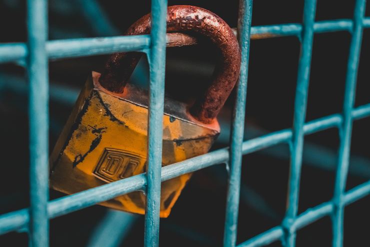 Rusty padlock on blue metal fence
